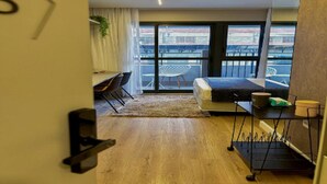 Een moderne kamer met een bed, een bureau en een balkon.