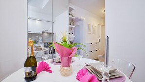 A modern dining area with a white table set for two, a bottle of wine, and a vase with flowers. - Awesome apartment in Mali Losinj with WiFi (Mali Losinj)