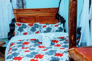 Un lit avec une couvre-lit à motifs floraux, une tête de lit en bois et un coussin décoratif blanc.