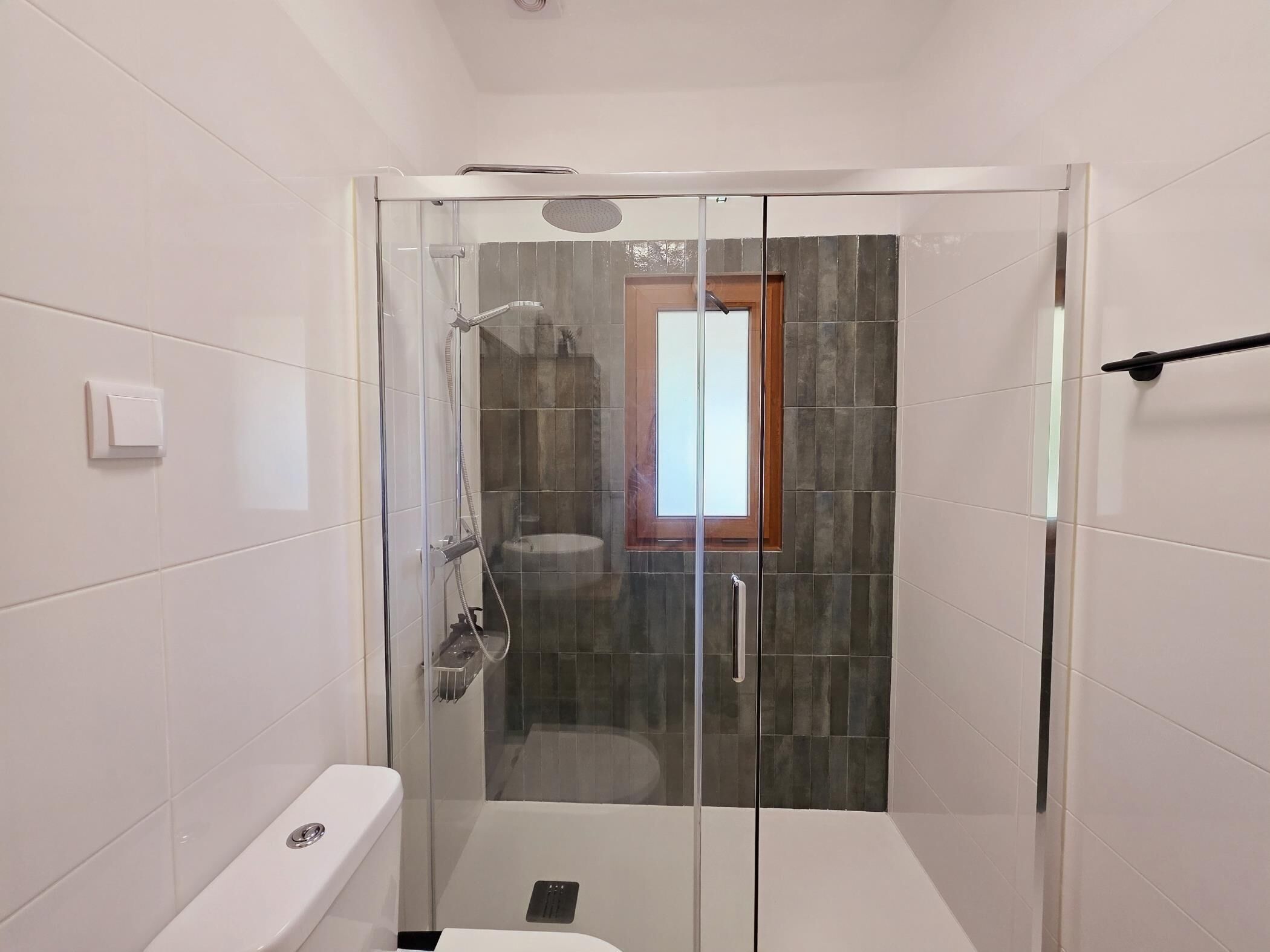 Un baño moderno con ducha acristalada, inodoro y lavamanos.