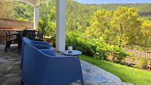 A covered outdoor seating area with stone flooring, a table, and chairs. - Cottage | Pool | Mountain View | Jacuzzi (Arganil)