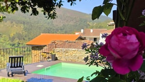 A garden with a swimming pool, a stone wall, and a chair. - Cottage | Pool | Mountain View | Jacuzzi (Arganil)