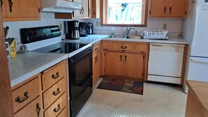 Una cocina compacta con armarios de madera, estufa, lavaplatos y refrigerador.