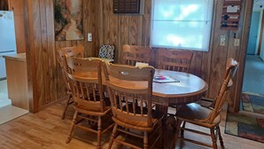 Una habitación con paneles de madera, una mesa redonda para comer y seis sillas.