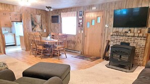 Una sala de estar acogedora con chimenea, un comedor y una cocina al fondo.