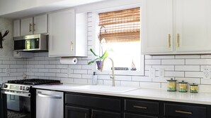 Una cocina moderna con armarios blancos, electrodomésticos de acero inoxidable y piso de madera.