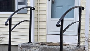 Una casa con una escalera de piedra y barandillas de metal negro.