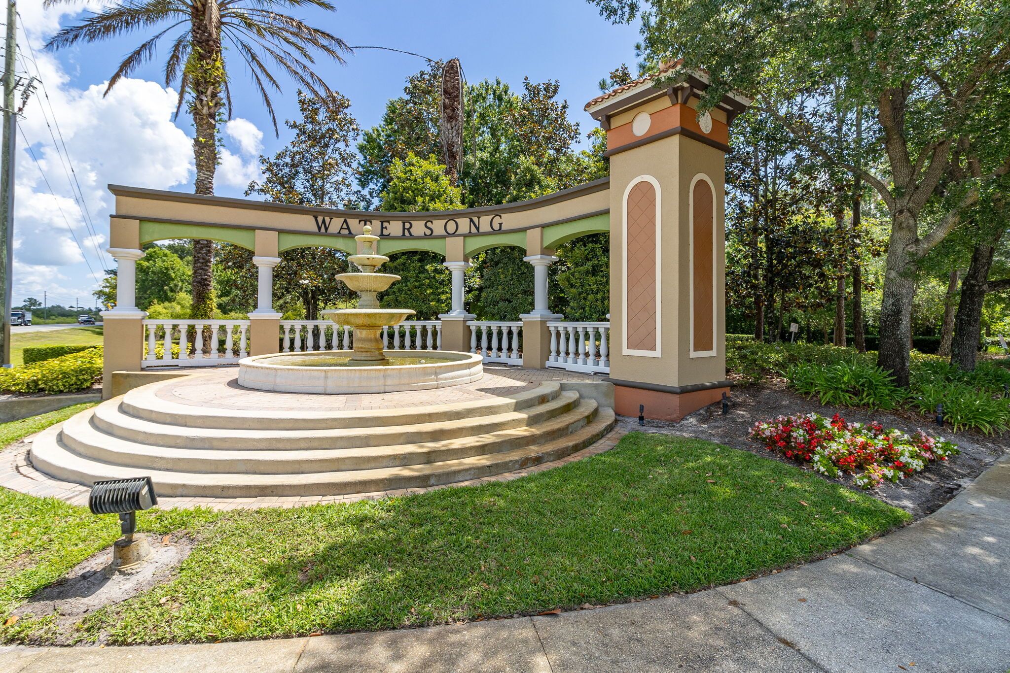 A landscaped area with a fountain, a sign reading "WATERSONG," and a well-maintained garden.