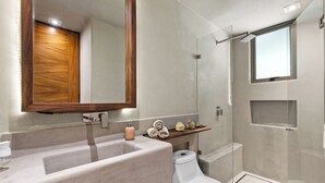 A modern bathroom with a large sink, a toilet, a shower enclosure, and a wooden vanity.