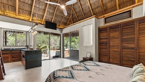 A spacious bedroom with a large bed, a ceiling fan, and a view of the outdoors through sliding glass doors.