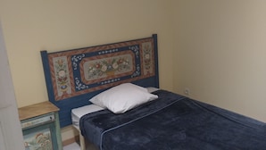 A small, single-bed room with a decorative headboard, a bedside table, and a plain wall. - Charming country house (Cours)