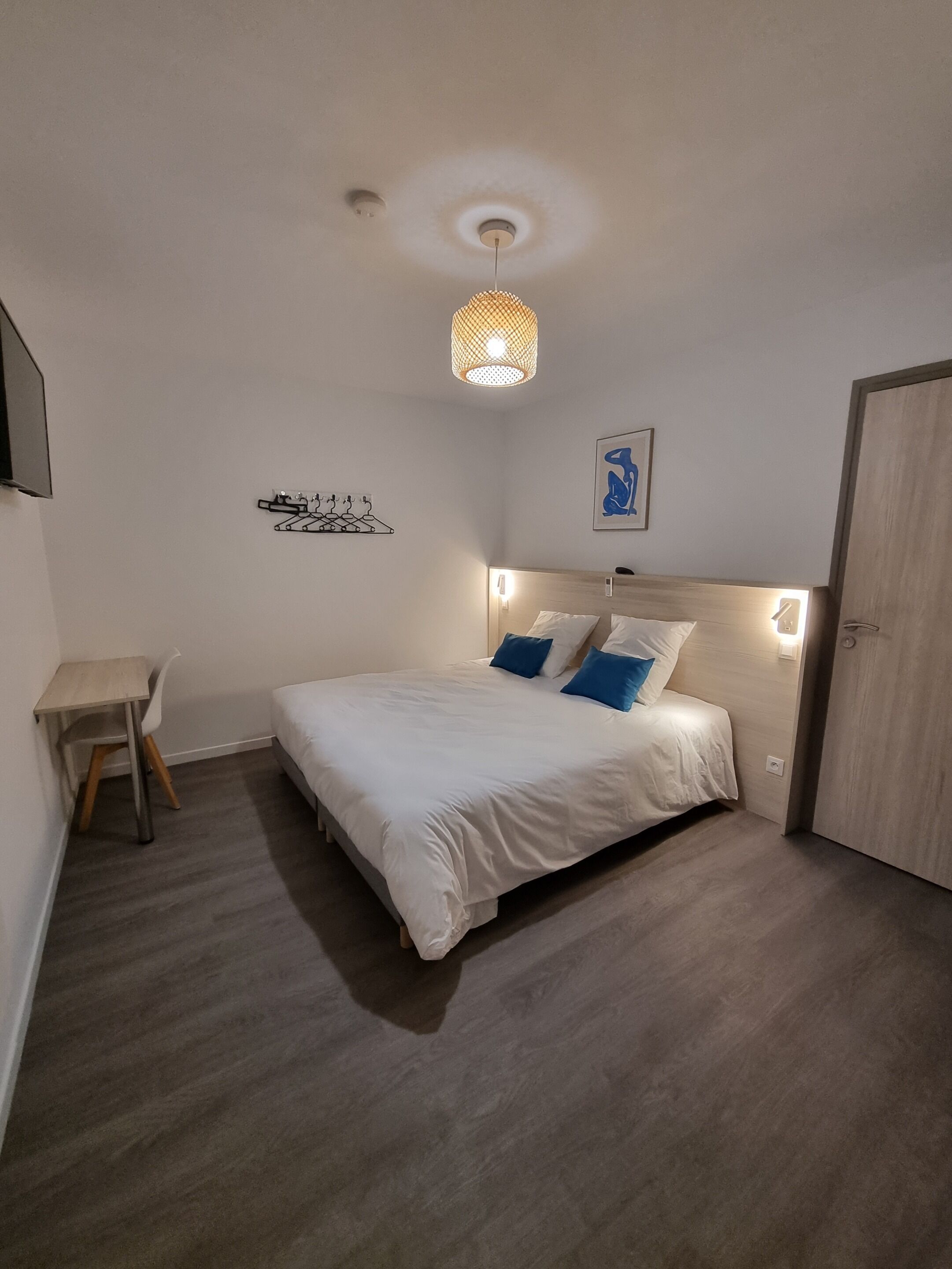 Et soveværelse med seng, natbord, stol og en hængende lampe.