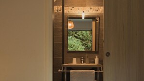 A hotel room with a bed, a bathroom with a mirror, a sink, and a towel rack. - Le Combo (Aix-les-Bains)