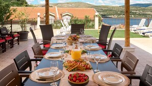 A dining table set outdoors with a view of a lake and hills. - Stunning home in Trogir (Trogir)