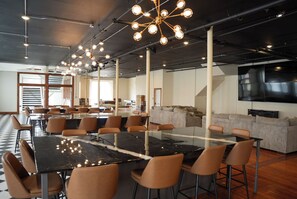 A spacious conference room with a large table, multiple chairs, and a modern chandelier.