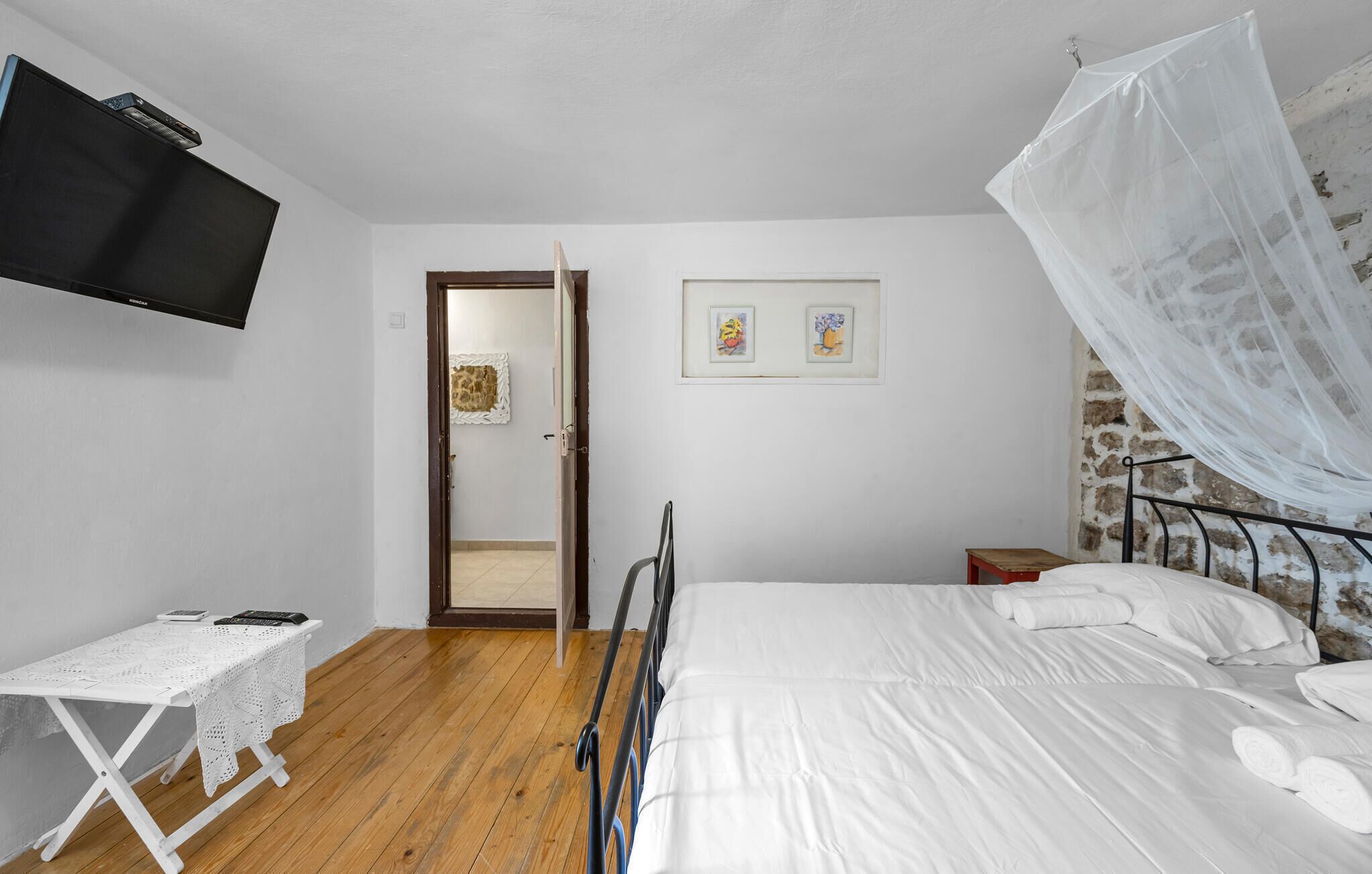 Une chambre à coucher avec un lit, un bureau, une télévision et des œuvres d’art accrochées au mur.