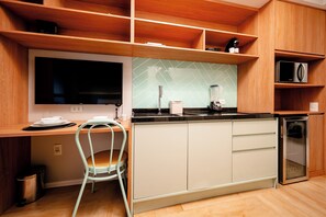 A kitchen with wooden cabinets, a microwave, a blender, and a small refrigerator.