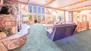 A cozy cabin interior with a stone fireplace, a leather sofa, and a dining area.