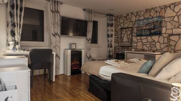 Un dormitorio moderno con chimenea, una cama con almohadas, un escritorio con silla y una pared de piedra con un cuadro.