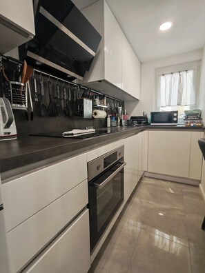 Een moderne keuken met een inbouwoven, magnetron en afzuigkap.