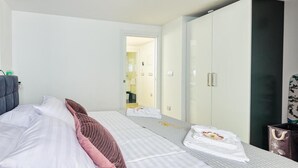 Ett hotellrum med en säng, en garderob, en spegel och en dörr som leder till ett annat rum.