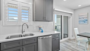 A modern kitchen with a double sink, stainless steel appliances, and a sliding glass door leading to a balcony.