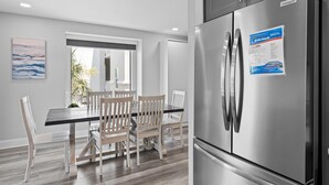 A modern kitchen with a stainless steel refrigerator, wooden dining table, and chairs.