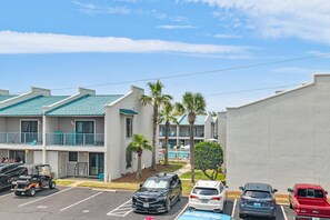 A multi-story hotel with a pool, parking lot, and palm trees. - Gulf Winds East #3 (Miramar Beach)