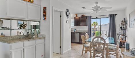 A kitchen with white cabinets, a granite countertop, and a dining area with a table and chairs.