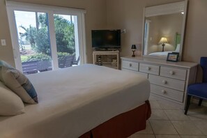 Una camera da letto con un letto, una televisione su un mobile, un comò e una sedia.