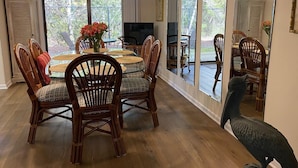 A dining area with a round table, wicker chairs, and a vase of flowers. - Gulf Winds East #36 (Miramar Beach)