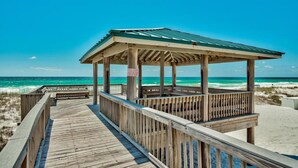 A wooden beach boardwalk leading to a gazebo with a green roof, overlooking the ocean. - Gulf Winds East #36 (Miramar Beach)