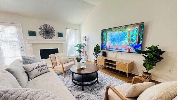 A living room with a sofa, armchairs, a coffee table, a TV, and a fireplace. - Charming 3-bedroom house  in delightful Katy! Perfect for family groups! (Katy)