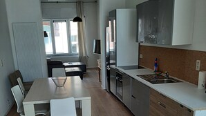 A modern kitchen with a dining area, wooden flooring, and white cabinetry.