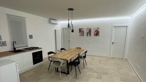 A compact kitchen with a dining area, featuring a wooden table and chairs, a built-in oven, and a white refrigerator. - Secretplace Palermo (Palermo)