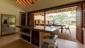 A kitchen with a large island, a refrigerator, and a dining area with a table and chairs. - Yeguas W27 by Wynwood House (Anapoima)