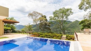 A swimming pool with a view of green hills and trees. - Yeguas W27 by Wynwood House (Anapoima)