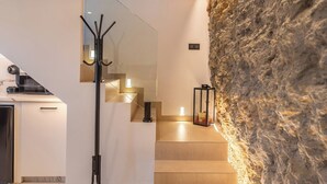 A modern interior with a stone wall, a staircase, and a coat rack. - Un Rinconcito en Setenil Setenil de las Bodegas by Ruralidays (Cádiz)