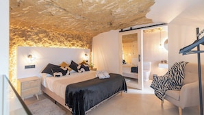 A bedroom with a bed, bedside tables, a chair, and a wardrobe. - Un Rinconcito en Setenil Setenil de las Bodegas by Ruralidays (Cádiz)