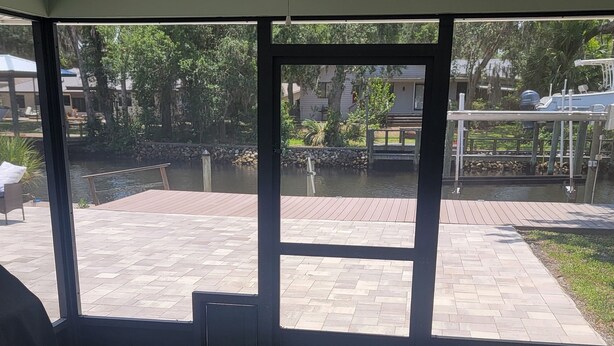 A room with large windows, a ceiling fan, and a view of an outdoor patio area. - Fisherman's Paradise w/ Waterfront and 2 KING suites. Bring your boat! 40' dock (Homosassa)