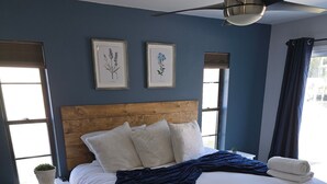 A bedroom with a large bed, a wooden headboard, a ceiling fan, and two framed botanical prints on the wall. - Fisherman's Paradise w/ Waterfront and 2 KING suites. Bring your boat! 40' dock (Homosassa)
