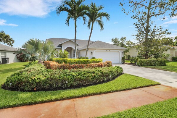 A residential house with a well-maintained lawn, palm trees, and a driveway leading to the garage. - Villa Napoli 3 bedroom Vacation dream in Naples FL (Naples)