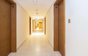 A hotel hallway with wooden doors, a tiled floor, and a ceiling light fixture.