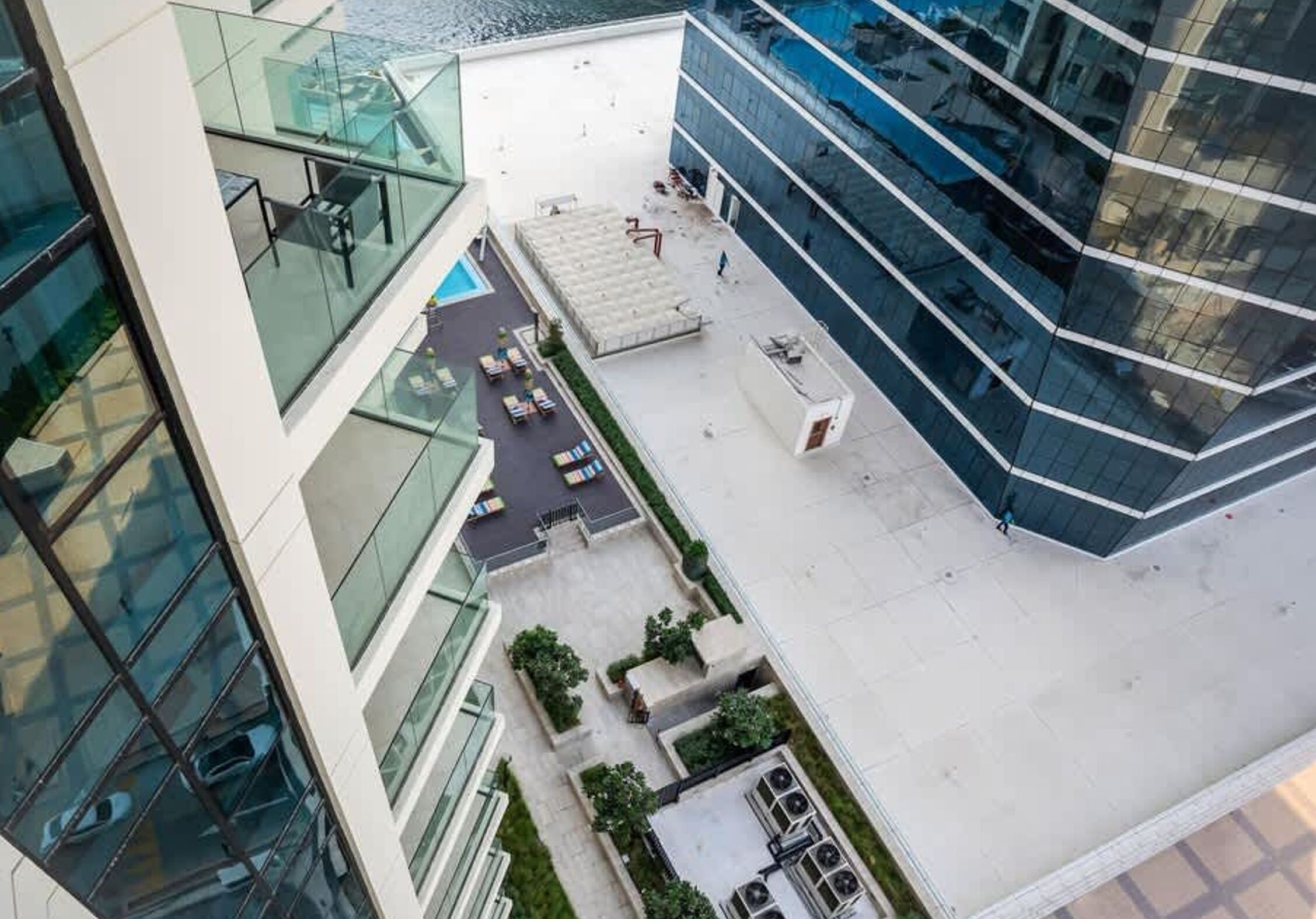 A modern building with a glass facade, outdoor seating area, and a small garden.
