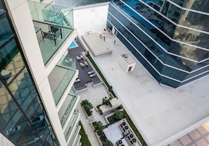 A modern building with a glass facade, outdoor seating area, and a small garden.