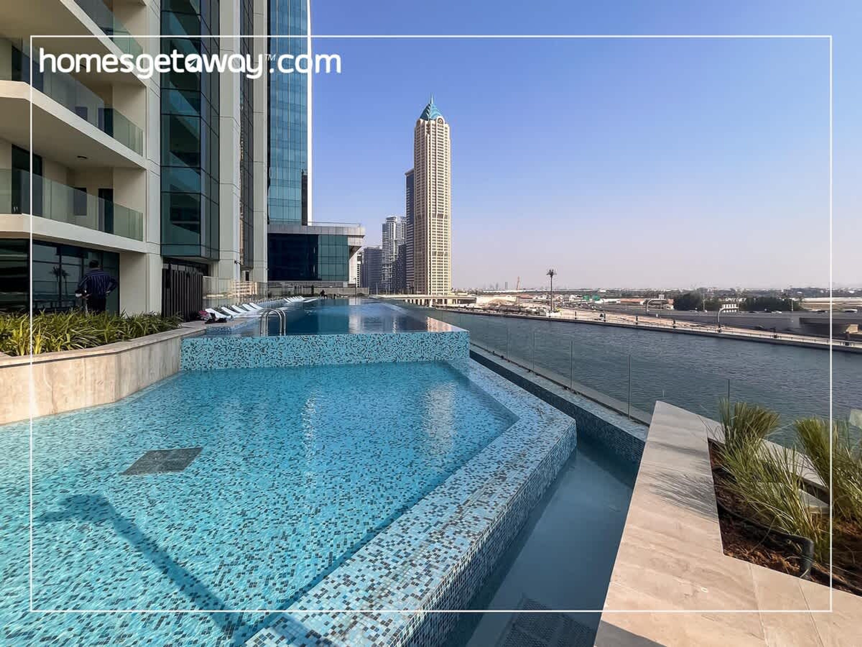 Una piscina moderna con vistas a un horizonte urbano y una masa de agua.