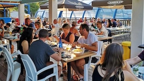 Un espace extérieur aménagé pour les repas, avec des tables et des chaises disposées sous un toit abrité.
