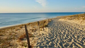 Une plage de sable bordée d’une clôture en bois, offrant une vue dégagée sur l’océan.