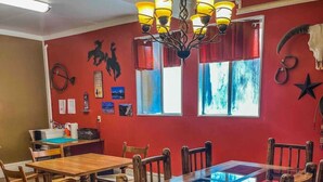 Un espace repas avec une table et des chaises en bois, un lustre et des murs rouges ornés de diverses décorations.