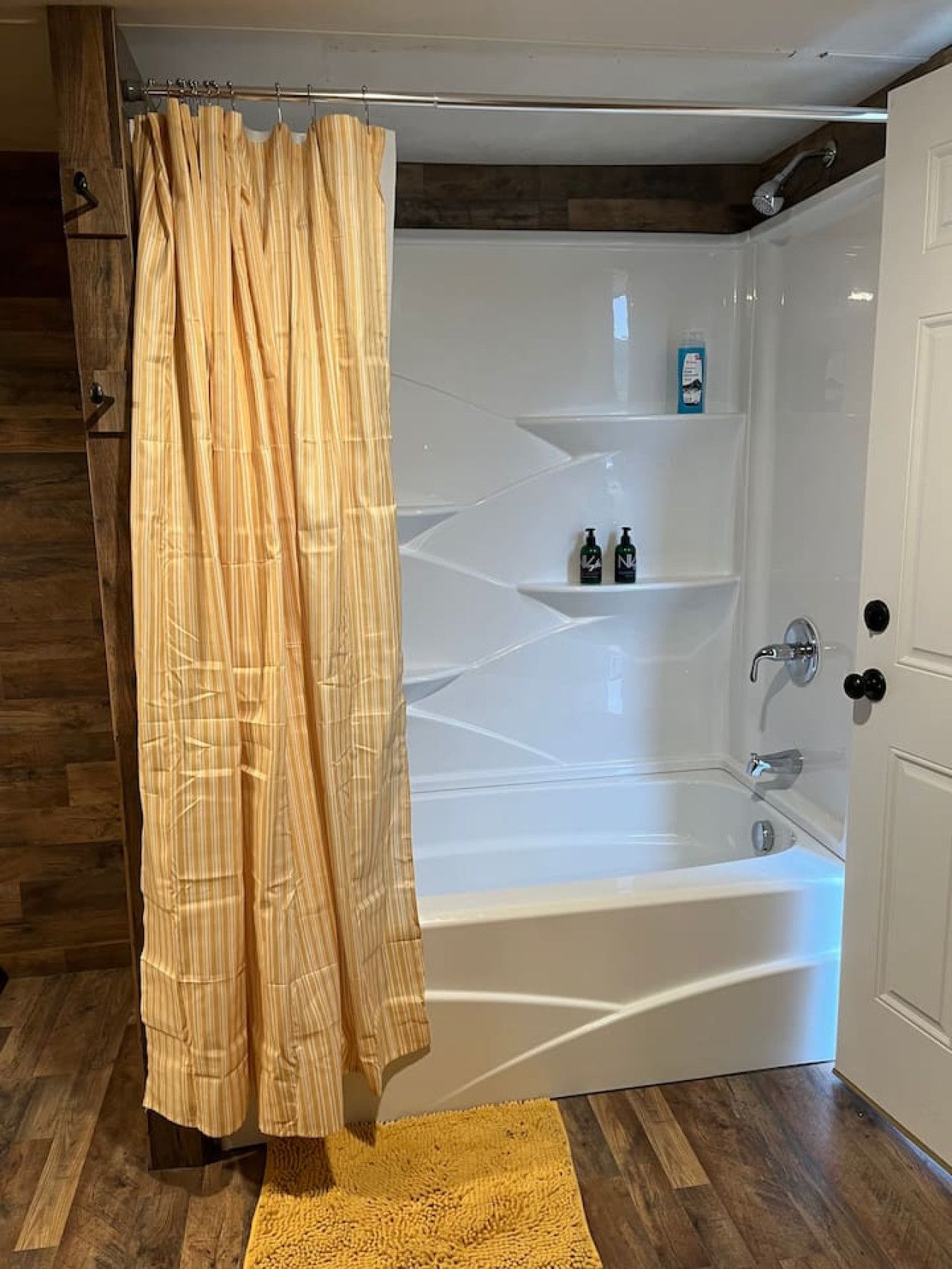 A modern bathroom with a freestanding bathtub, a showerhead, and a wooden floor.